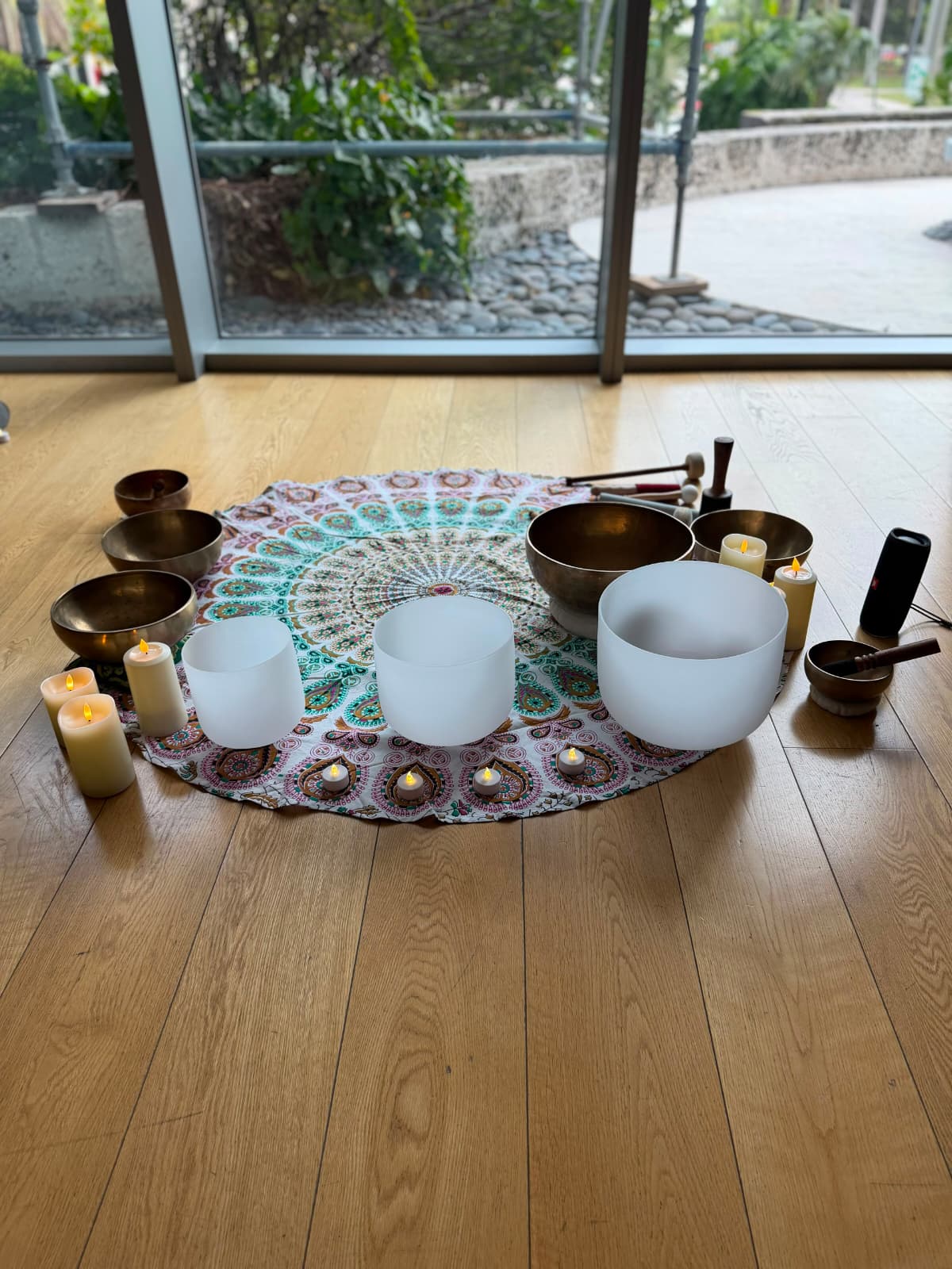 Crystal and Tibetan singing bowls with candles, arranged on a mandala cloth